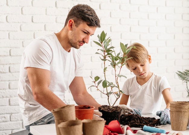 Free photo father and son planting plants at home