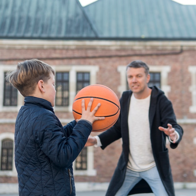 Free photo father and son playing basketball outdoors