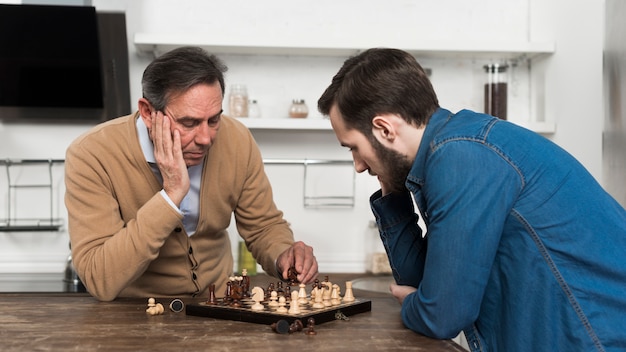 Free photo father and son playing chess in kithcen