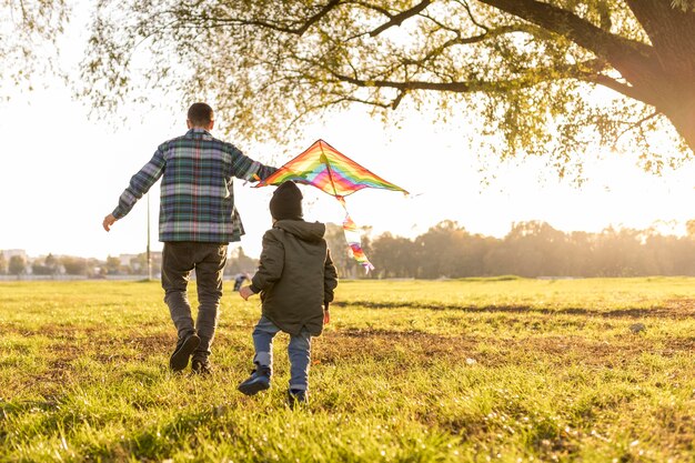 Father and son playing with a kite long view