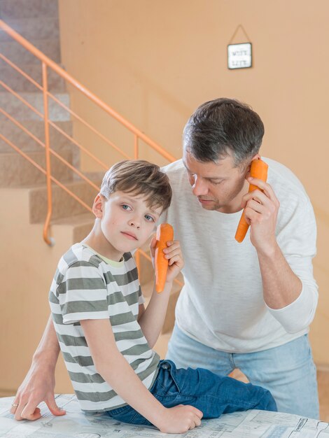 Father and son talking on carrot phones