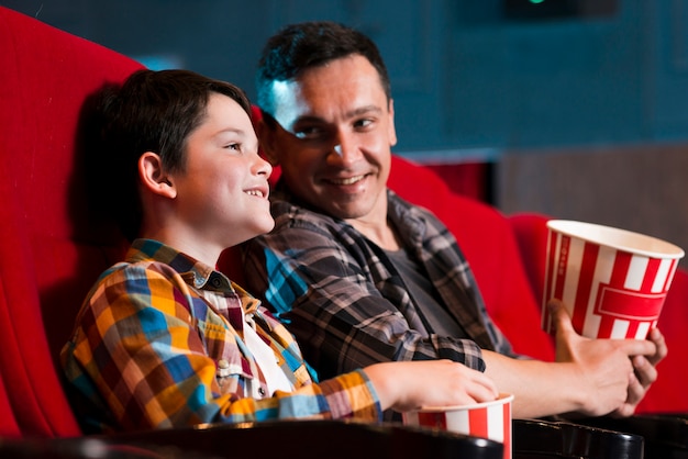 Free photo father and son watching movie in cinema