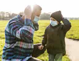 Free photo father and son wearing medical masks outdoors