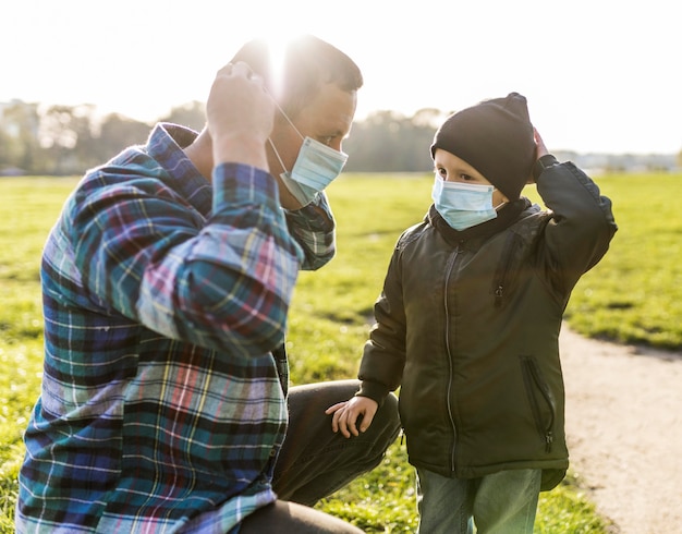 Free Photo father and son wearing medical masks outdoors