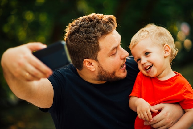 Free photo father taking a selfie and looking at his child