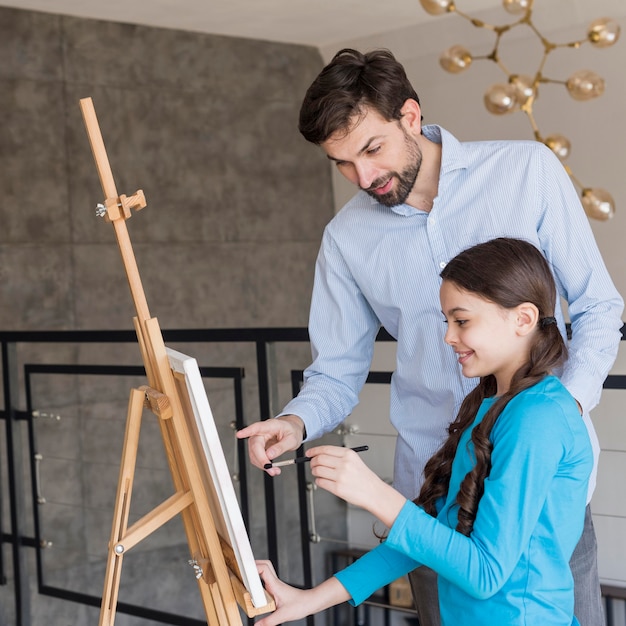 Father teaching girl to paint