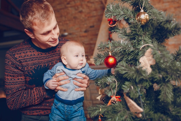 Free photo father with his baby in arms looking at the christmas tree ornaments