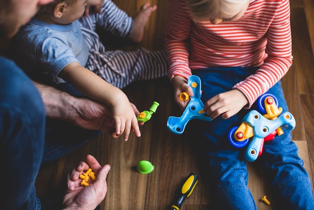 Free Photo father with his children putting together the pieces of a toy