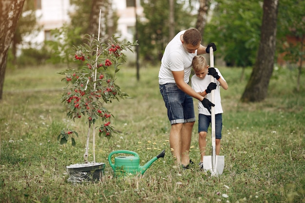 Free photo father with little son are planting a tree on a yard