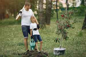 Free photo father with little son are planting a tree on a yard