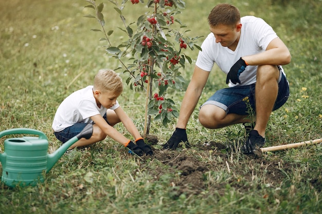 Free photo father with little son are planting a tree on a yard