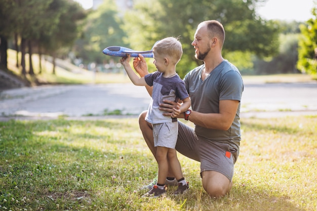 Father with son playing with toy plane at park