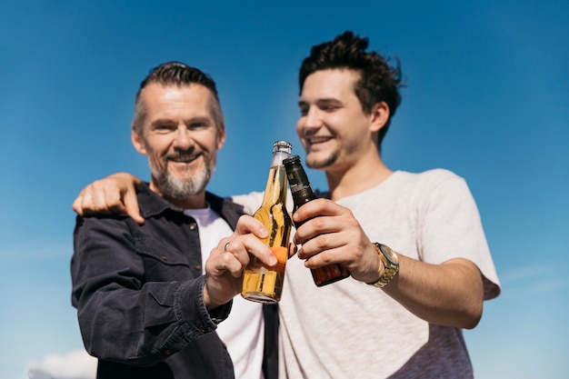 Fathers day concept with smiling father and son toasting with beer