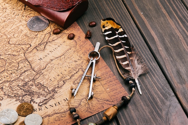 Free Photo feather, compasses, coffee beans, coins lie on old yellow map