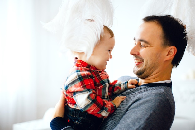 Free photo feathers hang over dad holding his little daughter