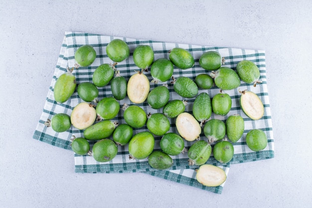 Feijoas on a folded tablecloth on marble background.