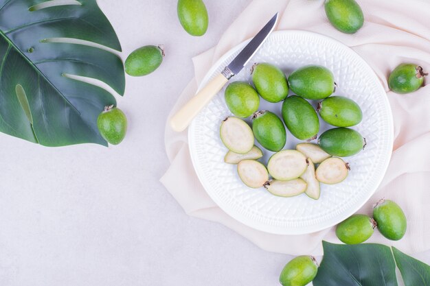 Feijoas in a white platter on grey surface