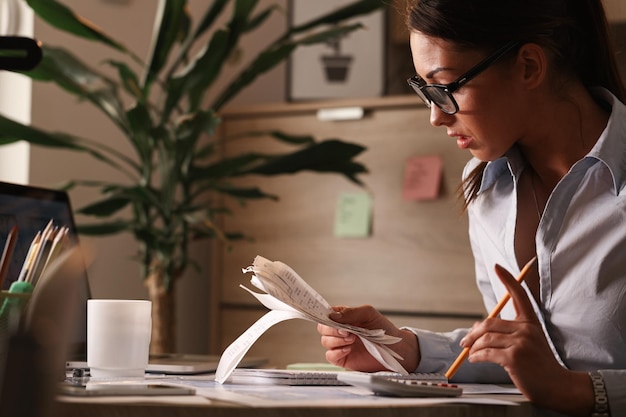 Female accountant calculating tax bills while working on finances in the office