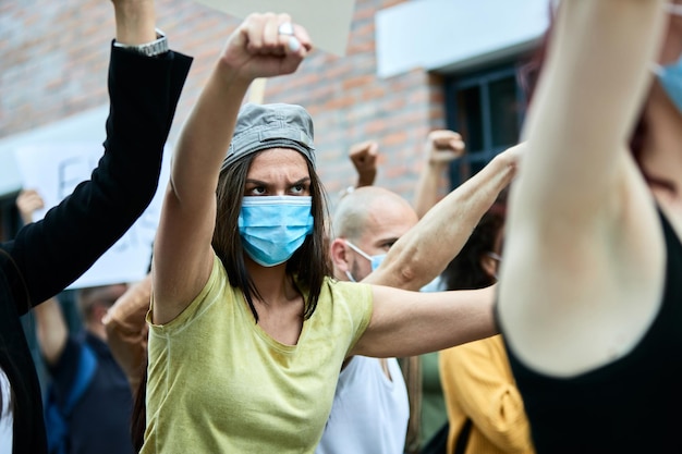 Free Photo female activist wearing protective face mask while protesting with crowd of people during covid19 pandemic