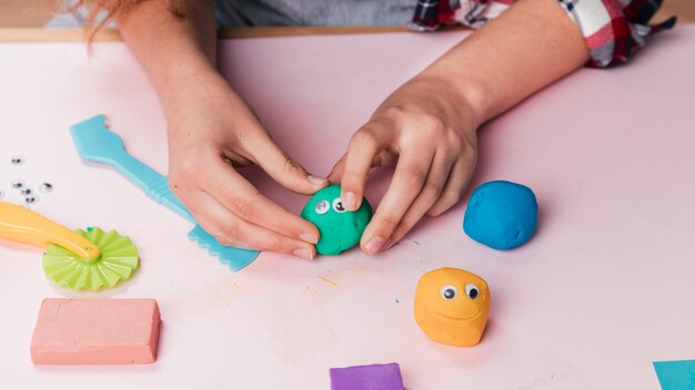 Female artist hand making cartoon faces using soft clay