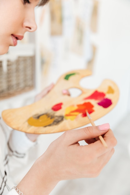 Free photo female artist holding palette and mixing paint colors