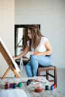 Free photo female artist painting on canvas in studio