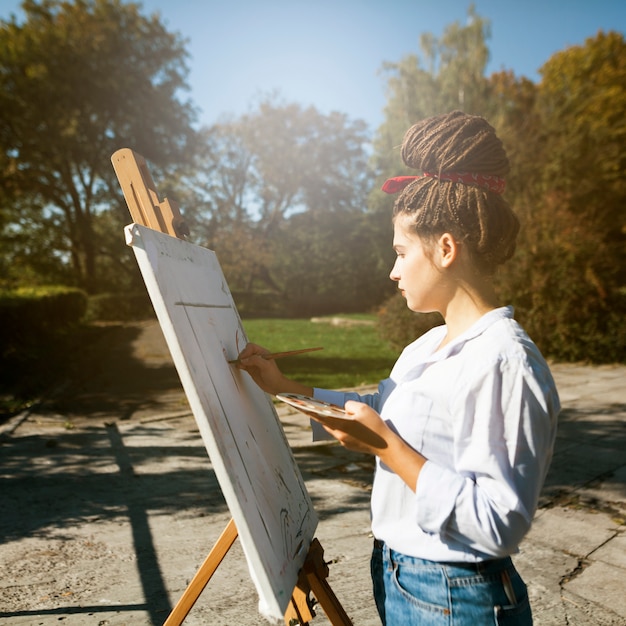 Free photo female artist painting outdoors