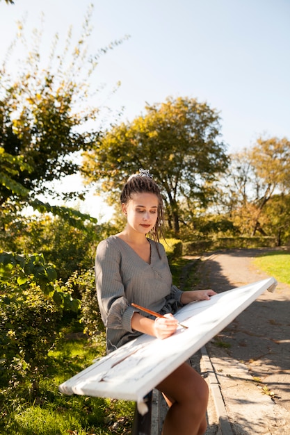 Free photo female artist painting outdoors