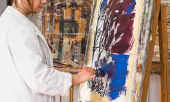 Free photo female artist painting with brush on canvas at workshop