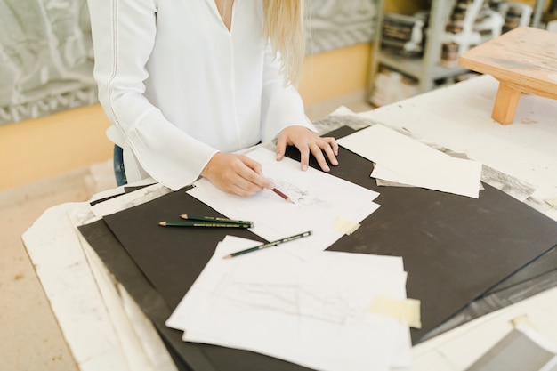 Female artist sketching on paper with pencil on table