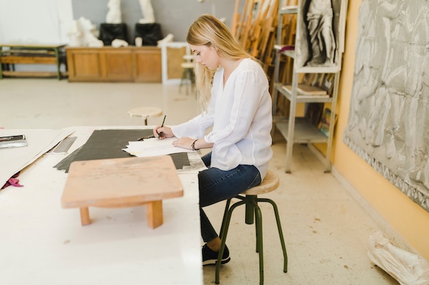 Female artist sketching on paper at workshop