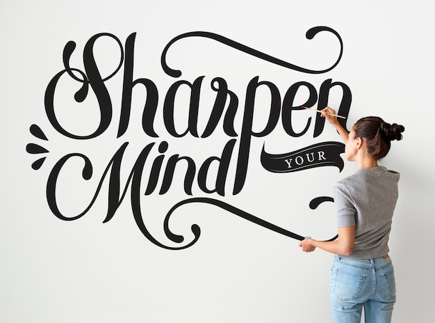 Free photo female artist writing sharpen your mind quote on the wall