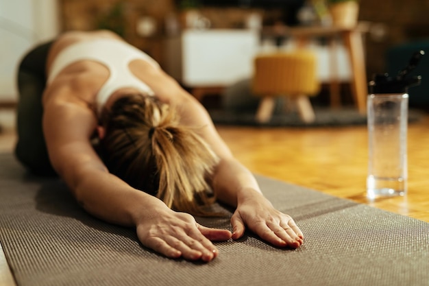 Female athlete doing relaxation exercises and stretching after sports training at home.