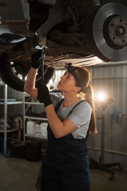 Free photo female auto repairer working in the shop on a car