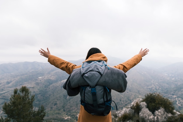 Free photo female backpacker standing on the top of mountain loving the nature