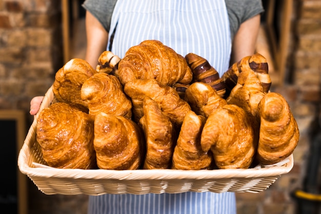 Female baker's hand holding basket of baked croissant