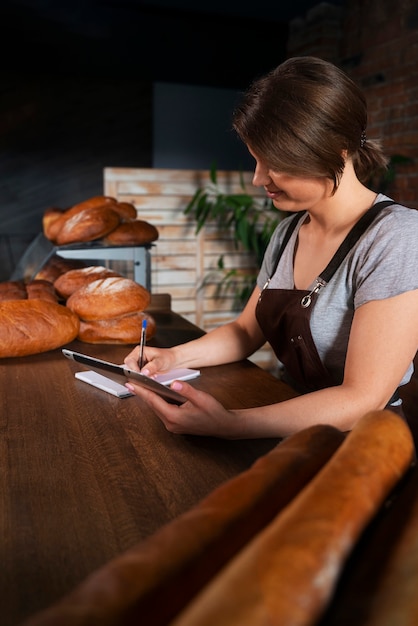 Free photo female baker in the shop with tablet taking online orders