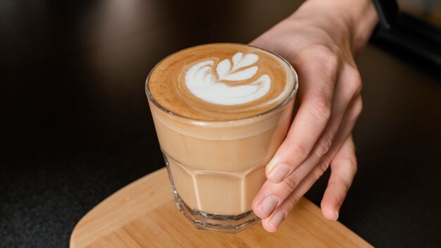 Female barista holding decorated coffee glass