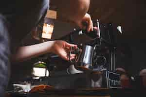 Free photo female barista prepares espresso from coffee machine in caf�