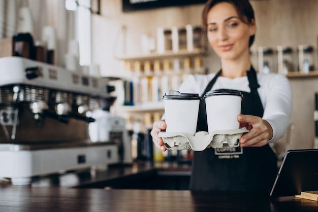 Female barista worker in a coffee shop holding coffee cup