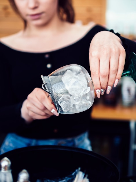 Female bartender preparing drink with ice