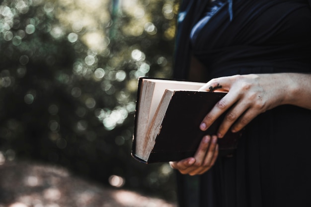 Female in black holding book in woods