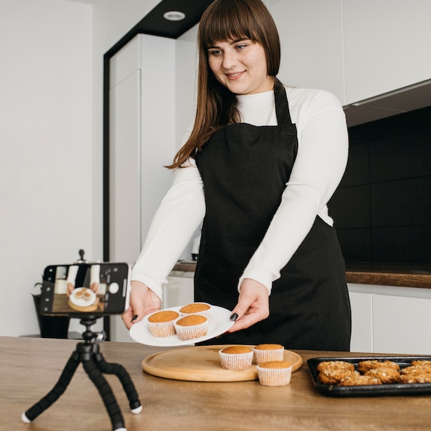 Female blogger recording herself while preparing muffins