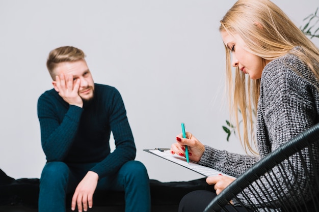 Free photo female blonde young psychologist consulting a male client during discussion therapy