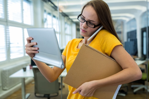 Free Photo female business executive holding a file and talking on mobile phone