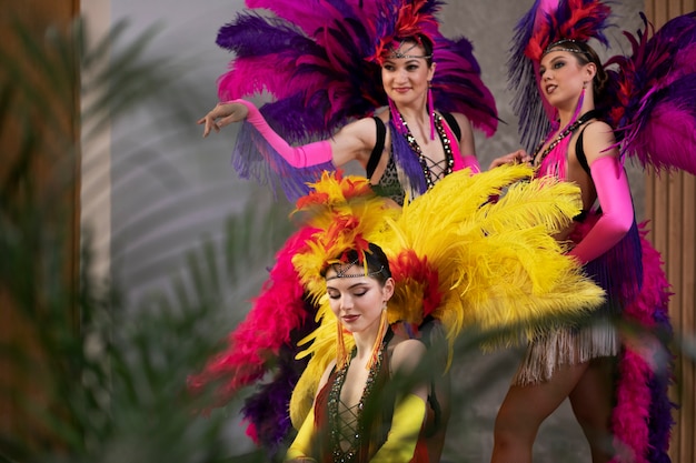 Female cabaret performers posing backstage in feathers costumes