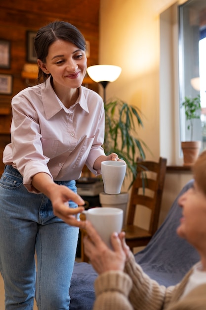 Free photo female caretaker at her client's house taking care of elderly person