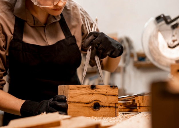 Free photo female carpenter in the office measuring piece of wood