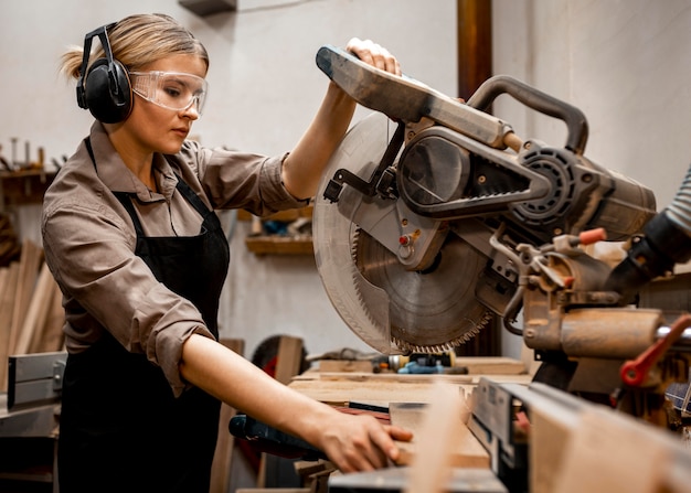 Free photo female carpenter using electric saw in the studio