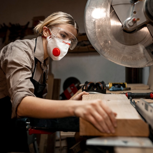 Free photo female carpenter using the round saw